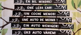 Yksi auto vähemmän -tarra on saatavilla kahdeksalla eri kielellä.